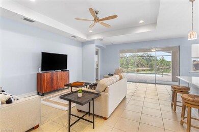 Living room with a ceiling fan, light tile patterned floors, a raised ceiling, recessed lighting, and baseboards