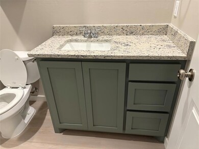 Bathroom with vanity, toilet, and wood finished floors