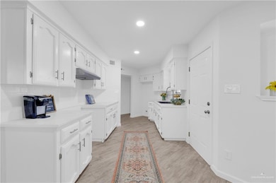 Kitchen with light countertops, tasteful backsplash, light wood-style floors, and recessed lighting