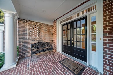 View of exterior entry featuring brick siding, french doors, and covered porch