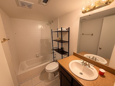 Bathroom with bathtub / shower combination, vanity, tile patterned floors, and a textured wall