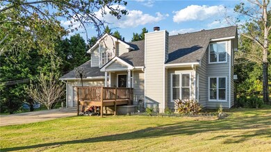 Rear view of property featuring roof with shingles, a yard, concrete driveway, and a chimney