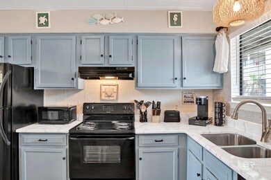 Kitchen featuring black appliances, under cabinet range hood, a sink, tasteful backsplash, and light stone counters