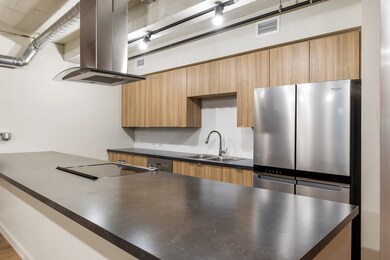 Kitchen with sink, island range hood, stainless steel refrigerator, black stovetop, and backsplash