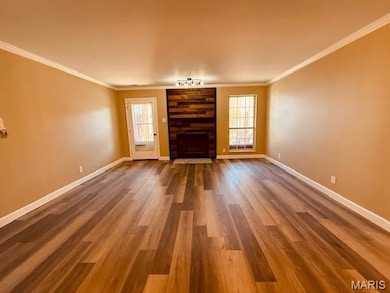 Unfurnished living room featuring ornamental molding, a fireplace, and wood finished floors
