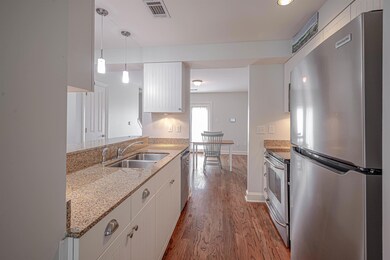 Kitchen featuring stainless steel appliances, a sink, wood finished floors, and white cabinetry