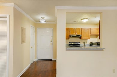 Kitchen with stainless steel microwave, under cabinet range hood, range with electric stovetop, electric panel, and dark wood-style flooring