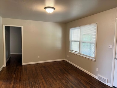 Unfurnished room with dark wood-style floors and baseboards