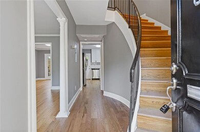 Entryway featuring wood finished floors, stairway, and ornate columns
