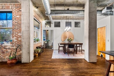Dining space with dark wood-style floors, brick wall, and a towering ceiling