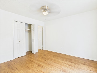 Unfurnished bedroom featuring light wood-style flooring, a closet, and a ceiling fan