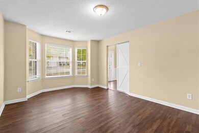 Unfurnished room with dark wood-style floors, a textured ceiling, and a barn door