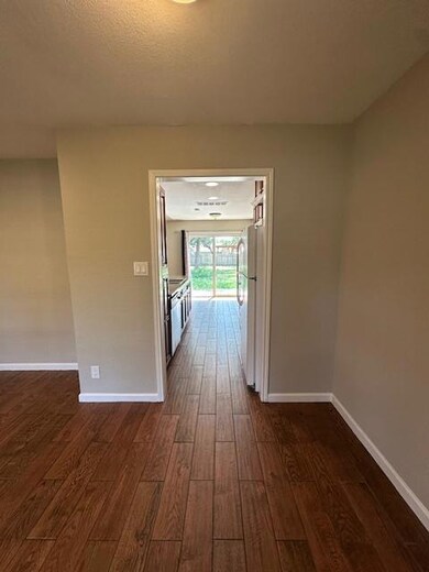 Corridor with dark wood-style flooring and basebo