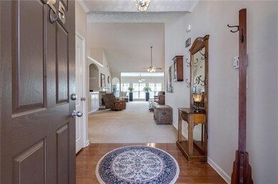 Foyer entrance with arched walkways, ceiling fan, baseboards, high vaulted ceiling, and wood finished floors