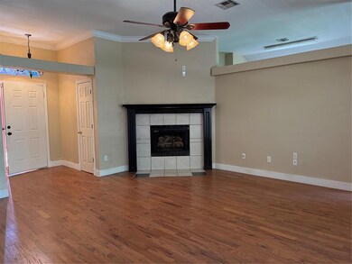 Living room with crown molding, wood finished floors, a ceiling fan, fireplace