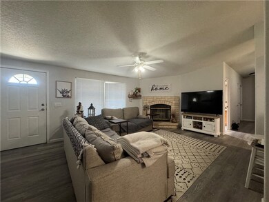 Living area featuring a fireplace, dark wood-style flooring, a textured ceiling, and plenty of natural light