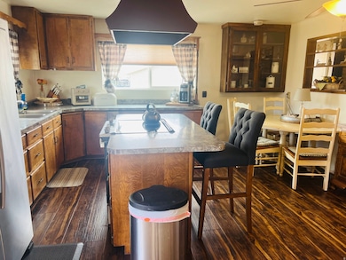 Kitchen with a kitchen breakfast bar, exhaust hood, freestanding refrigerator, and dark wood-type flooring