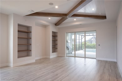 Spare room with beamed ceiling, built in features, light wood-style floors, and recessed lighting