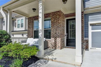 Entrance to property featuring covered porch, brick siding, and a garage
