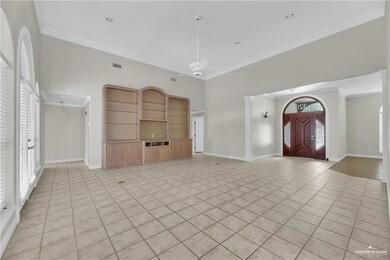 Unfurnished living room featuring ornamental molding, light tile patterned floors, ceiling fan, and a high ceiling