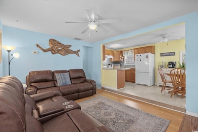Living room with ceiling fan, light wood-style floors, and a textured ceiling