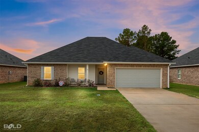 View of front facade featuring a yard, driveway, a garage, and brick siding