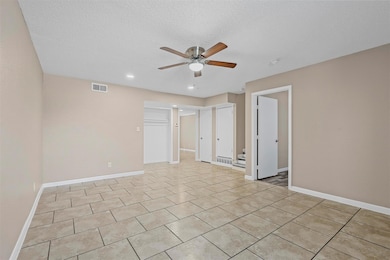 Spare room with ceiling fan, a textured ceiling, v