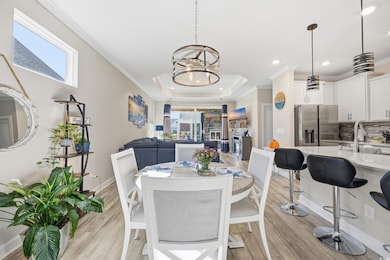 Dining space with a tray ceiling, ornamental molding, light wood-style flooring, a chandelier, and recessed lighting