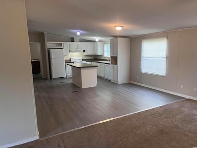 Kitchen featuring white appliances, white cabinetry, a kitchen island, dark countertops, and under cabinet range hood