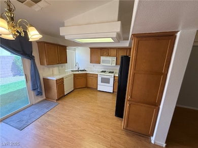 Kitchen featuring white appliances, a sink, light