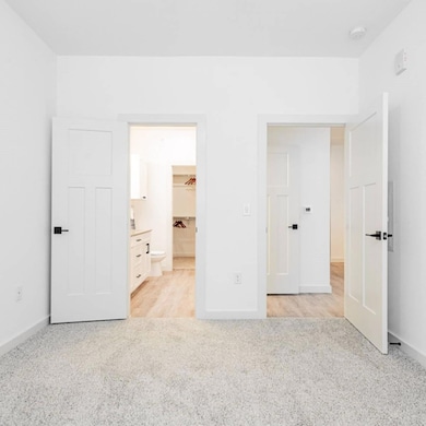 Unfurnished bedroom with light carpet, ensuite bat