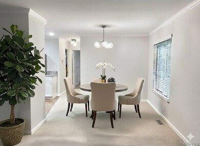 Dining room (Virtually Staged) with ornamental molding, a chandelier, and light carpet