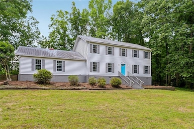 Colonial-style house featuring metal roof, a front yard, and crawl space