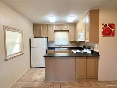 Kitchen with sink, white appliances, a wealth of natural light, light tile patterned flooring, and kitchen peninsula