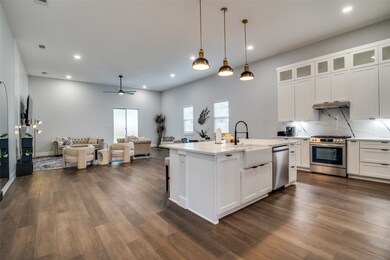 Kitchen featuring white cabinets, decorative light fixtures, open floor plan, a ceiling fan, and appliances with stainless steel finishes