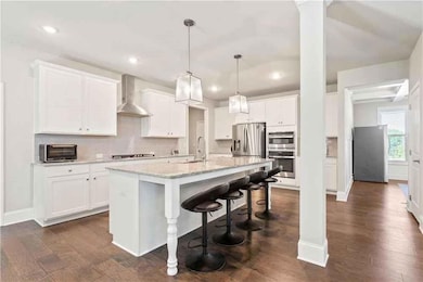 Kitchen featuring wall chimney range hood, an isla