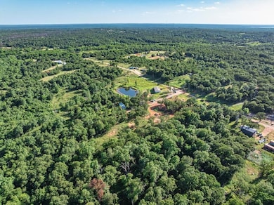 Aerial view of property and surrounding area with a forest and a large body of water