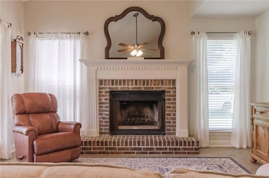 Carpeted living area with a fireplace and a ceiling fan