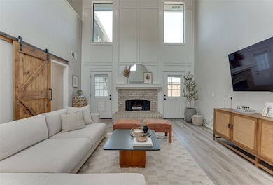Living area with a high ceiling, a barn door, wood finished floors, and a brick fireplace