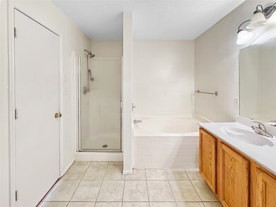 Bathroom with a bath, vanity, light tile patterned flooring, a shower stall, and a textured ceiling