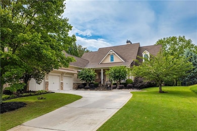 View of front facade featuring a front yard, covered porch, driveway, stone siding, and a chimney