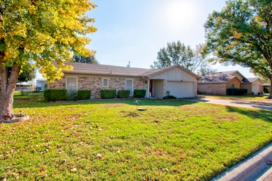 Ranch-style house featuring brick siding, driveway, board and batten siding, and a garage