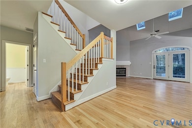 Stairway with a skylight, wood finished floors, a tile fireplace, ceiling fan, and a high ceiling