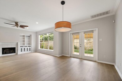 Unfurnished living room featuring a tiled fireplace, french doors, light wood-style flooring, ornamental molding, and built in shelves
