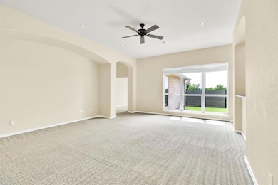 Carpeted empty room with a ceiling fan, arched wa