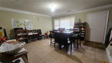 Dining area with a textured ceiling, tile patterned flooring, crown molding, and an office area