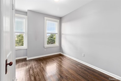 Unfurnished room featuring dark wood finished floors and baseboards