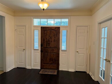 Entry foyer featuring ornamental molding, dark hardwood flooring, and double coat closets