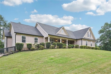 View of front of home featuring board and batten siding, a front yard, stone siding, and a shingled roof