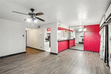 Unfurnished living room featuring ceiling fan, wood finished floors, and a chandelier